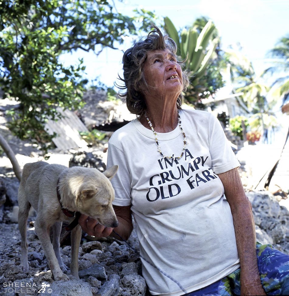Erlene has no water or electricity. She gets water from a standpipe down the road and uses a kerosene lamp for light. She heats water once a week on this outside stove to have a wash. Her dog is a constant companion and she has a strong belief in the Almighty.